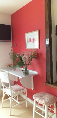 a red wall with a white desk and two chairs at Logis Auberge Du Centre in Chitenay
