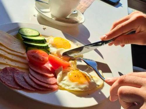a person cutting up a plate of breakfast food at Kolochava Eco Resort in Kolochava