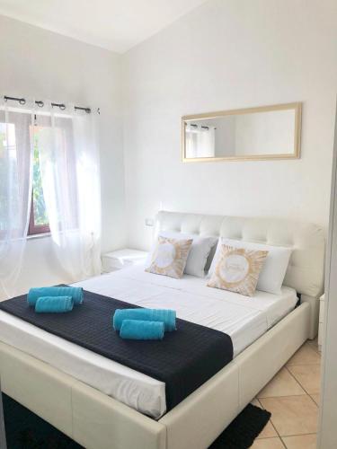 a white bed with blue pillows on top of it at International House San Teodoro in San Teodoro