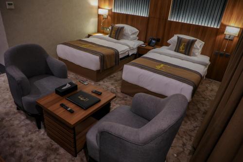 une chambre d'hôtel avec deux lits et deux chaises dans l'établissement فندق ايي E Hotel, à Médine