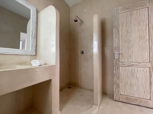 a bathroom with a sink and a mirror and a door at Airamjudi in Watamu