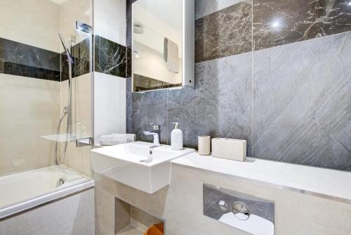a white bathroom with a sink and a shower at London Paddington Apartment in London