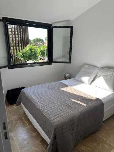 une chambre avec un lit et une grande fenêtre dans l'établissement Les catalanes du golf, à Saint-Cyprien