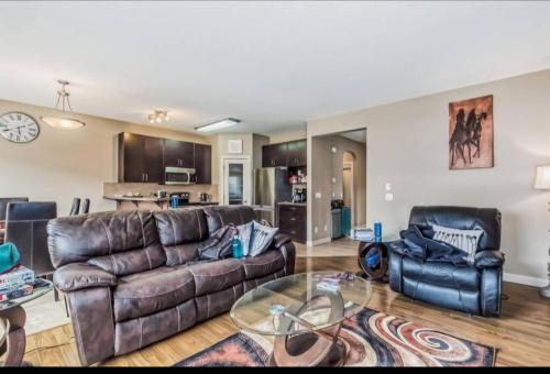 a living room with a leather couch and two chairs at Rome, Sweet Home in Calgary