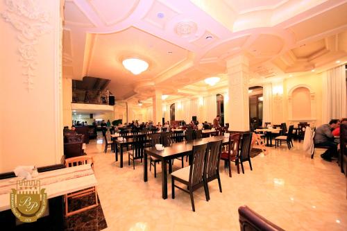 a restaurant with tables and chairs and people sitting at them at Borjomi Palace Health & Spa Center in Borjomi