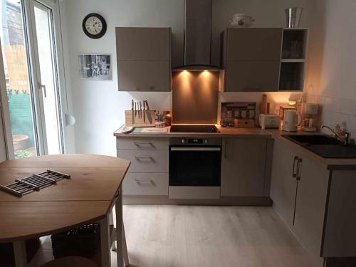 une cuisine avec des armoires blanches et une table en bois dans l'établissement Cocon dans l'artère du centre-ville, à Reims