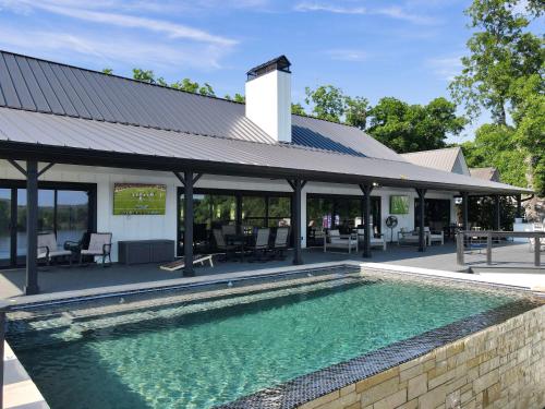 a swimming pool in front of a house with a roof at River Oaks Luxury Lakeshore Concierge Services Available in Kingsland