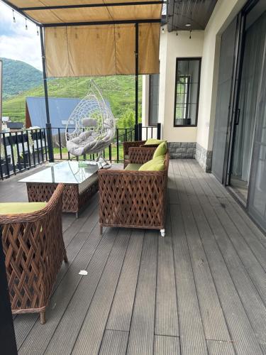 a patio with wicker furniture and a swing at Панорамным видом на лесные горы Panorama ART in Artavaz