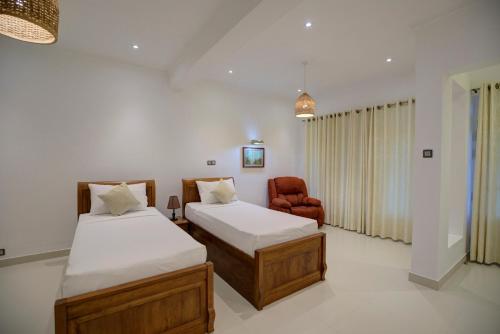 a bedroom with two beds and a chair in it at Rose Hill Bungalow in Gampola