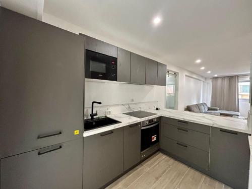 une cuisine avec des armoires grises et un évier dans l'établissement Le Cosy, au Cannet