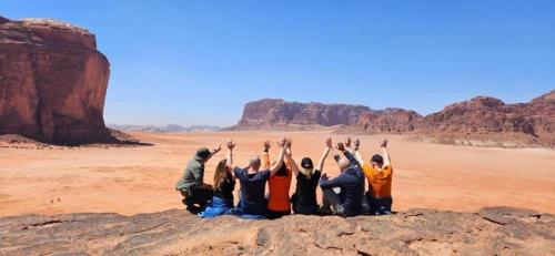 a group of people sitting on a rock in the desert at Wadi Rum Faris in Wadi Rum