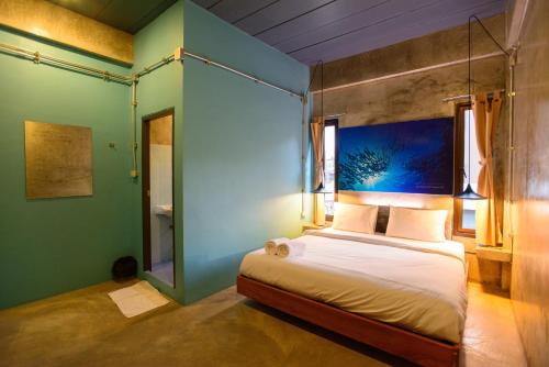 a bedroom with a bed and a blue wall at Seabox Khaolak Hostel in Khao Lak