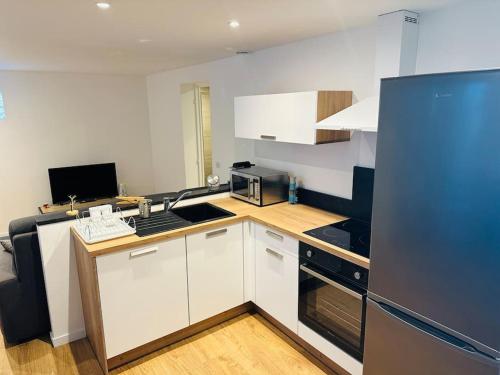 une cuisine avec des armoires blanches et des appareils noirs dans l'établissement Appartement en rez-de-maison, à Nice