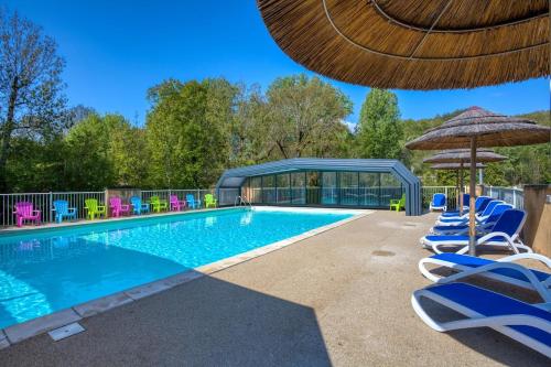 une piscine avec des chaises et un parasol dans l'établissement Camping Le Douzou, à Bouzic
