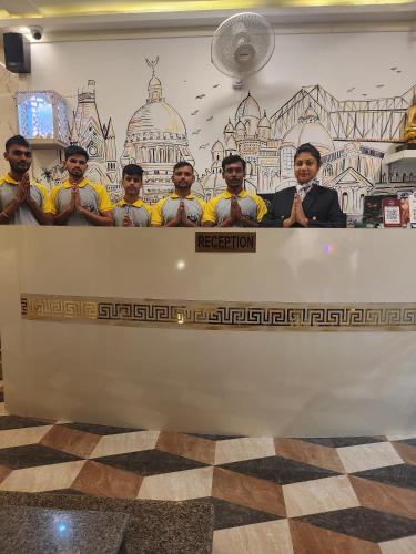 a group of men standing behind a table at The City of Joy in Kolkata