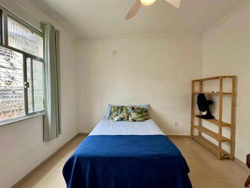 une chambre avec un lit avec une couverture bleue et une fenêtre dans l'établissement Hostel Casinha Tropical, à Rio de Janeiro