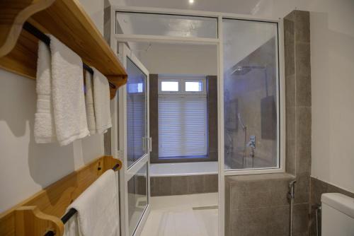 a bathroom with a shower and a glass shower backdoor at Rose Hill Bungalow in Gampola