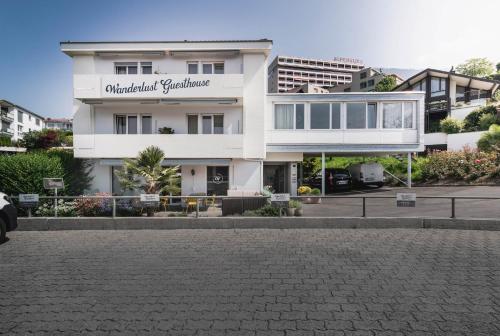 a white building with a sign on it at Wanderlust Guesthouse in Weggis
