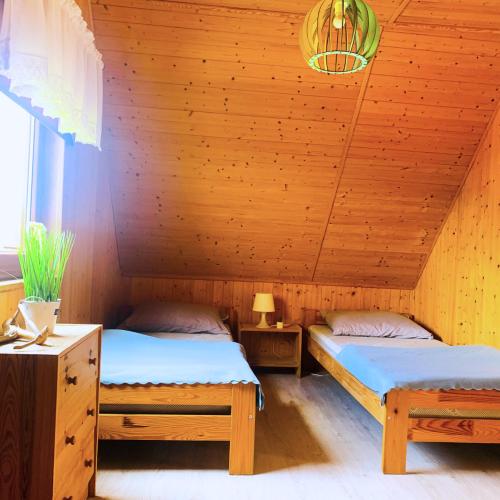 two beds in a room with a wooden ceiling at Domek letniskowy Magda in Łeba