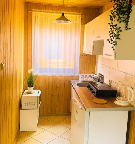 a kitchen with white cabinets and a sink and a window at Domek letniskowy Magda in Łeba