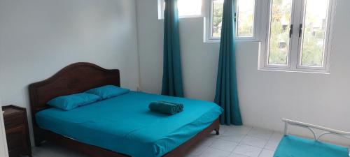 a bedroom with a bed with blue sheets and windows at Furnished Townhouse - Grand Baie in Grand Baie