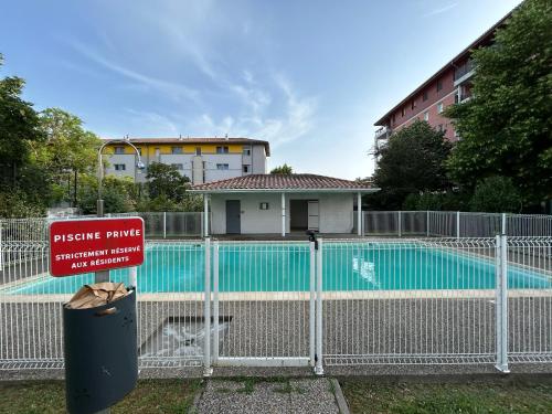 une clôture devant une piscine avec un panneau dans l'établissement Appartement cosy Agen centre avec Lit King Size, à Agen