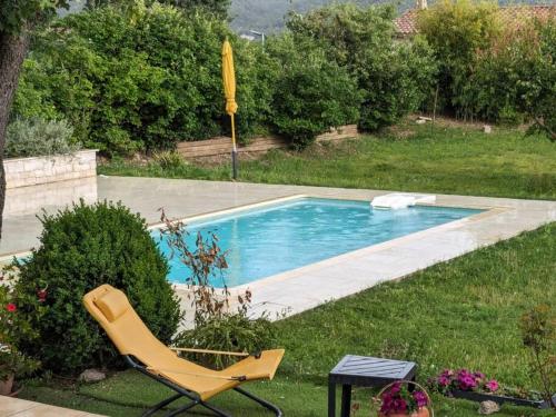 a yellow chair and a swimming pool in a yard at Villa calme avec piscine à Greoux in Gréoux-les-Bains