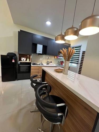 a kitchen with a counter and two black chairs at RUMAH CAMAR by IMPIAN HOMESTAY KLIA - SALAK TINGGI - NILAI in Sepang