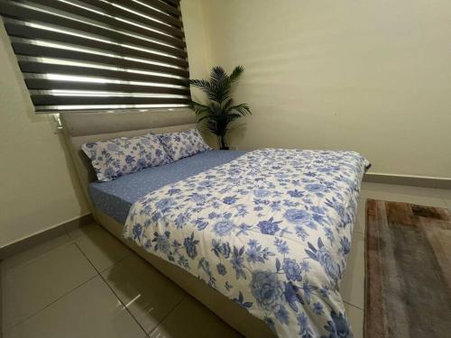 a bed with a blue and white blanket and a window at RUMAH CAMAR by IMPIAN HOMESTAY KLIA - SALAK TINGGI - NILAI in Sepang