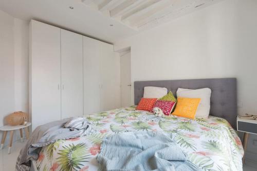 une chambre avec un grand lit avec des oreillers colorés dans l'établissement Centre Montorgueuil - Sunny and stylish flat, à Paris