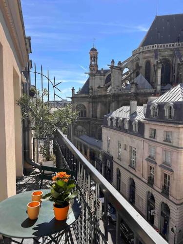un balcon avec une table avec des fleurs et un bâtiment dans l'établissement Centre Montorgueuil - Sunny and stylish flat, à Paris
