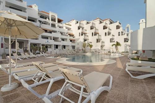 een resort met een zwembad en stoelen en een gebouw bij Luxury Penthouse Sea View Jacuzzy & pool wiffi free in Playa Fañabe