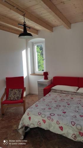 a bedroom with a bed and a chair and a window at Chilometro 29 aria in Dervio