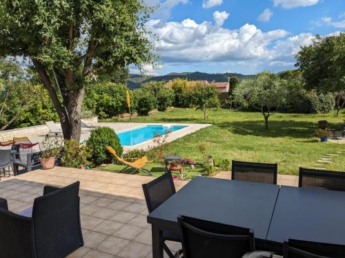 a patio with a table and chairs and a swimming pool at Villa calme avec piscine à Greoux in Gréoux-les-Bains