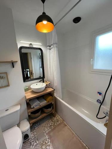 une salle de bain avec un lavabo, des toilettes et un miroir dans l'établissement Maison à 5 mn à pied de la plage, à Soulac-sur-Mer