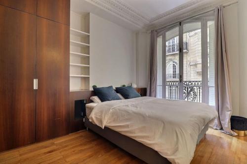 une chambre avec un lit et une grande fenêtre dans l'établissement Luxury 3 Bedrooms Apartment near Champs Elysees, à Paris