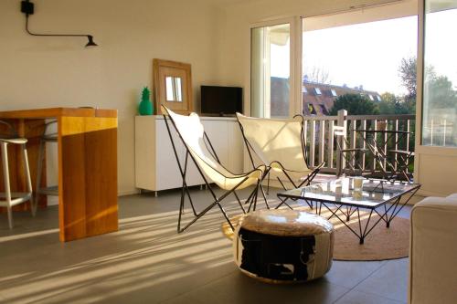 Appartement Le Clos de Sablier في تورجفيل: غرفة معيشة مع كراسي وطاولة وأريكة