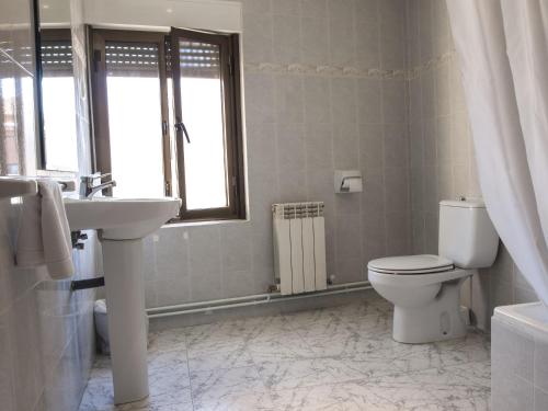 baño con aseo y lavabo y ventana en Hostal Nicolás en Medinaceli