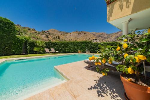 a swimming pool with a lemon tree next to a house at Villa Almond in Taormina