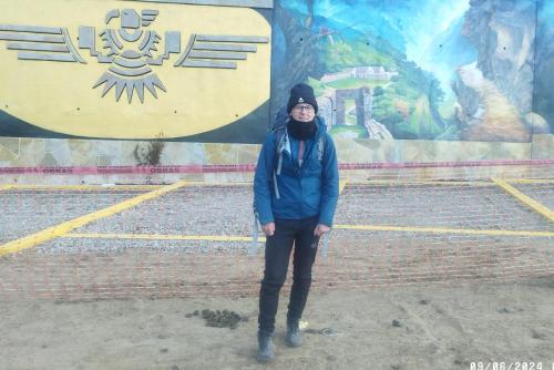 a woman is standing in front of a mural at the wooden house choquequirao in Cachora