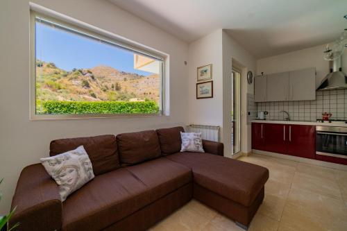 a living room with a brown couch and a large window at Villa Almond in Taormina