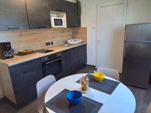 Il comprend une cuisine équipée d'une table blanche et d'un réfrigérateur. dans l'établissement Le bon plan entre Caen et la mer ** Draps et ménage inclus !**, à Giberville