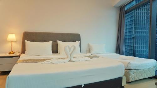 a bedroom with two beds with white sheets and a window at MOONWAY SUITES At EATON KLCC in Kuala Lumpur