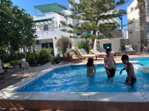 a group of kids playing in a swimming pool at Ioanna Apartments in Agios Prokopios
