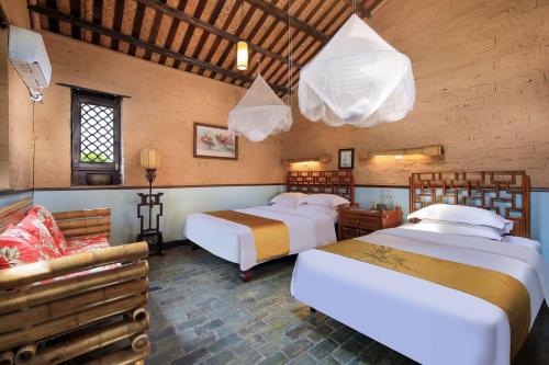 a bedroom with two beds and a couch at Yangshuo Village Inn Boutique Hotel in Yangshuo