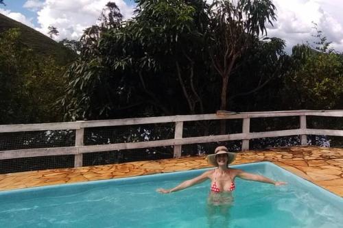 a woman in a hat in a swimming pool at Chalé com vista para montanha na CERVEJARIA JYBÁ in Itajubá