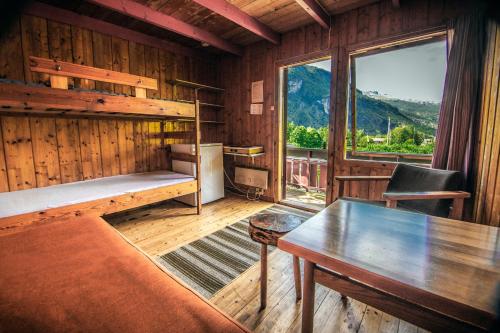 a room with a bunk bed and a table and a window at Pluscamp Sandvik in Gaupne