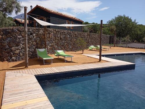 une piscine avec deux chaises et un bâtiment dans l'établissement PODERE DELL'ETNA SEGRETA - Essential Nature Hotel, à Biancavilla