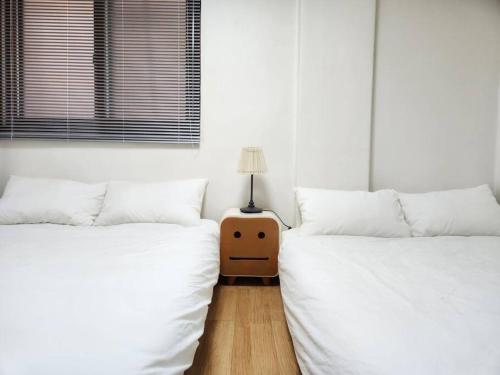 2 letti con lenzuola bianche e un tavolo con una lampada di Relaxing in Downtown a Seul