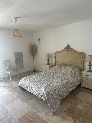 a bedroom with a bed and two tables and a chair at Appartement provençal in Mirabel-aux-Baronnies